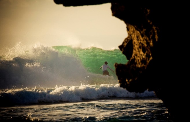 A surfer rides out a wave at Uluwatu near its famous cave.