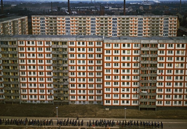 East Germany, East Berlin 1975. Mass housing for workers in Weissensee district (Plattenbau) with a demonstration of FDJ youth passing by .