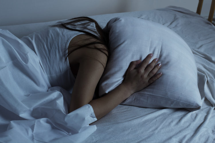Girl covered her head with a pillow.Insomnia