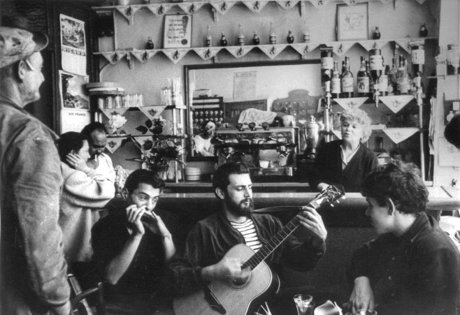 Peter Golding (harmonica), Robin Page (guitar) amd Madame Rachou (behind counter) as seen in THE BEAT HOTEL, a film by Alan Govenar. A First Run Features release. Photo credit: Harold Chapman, 1960