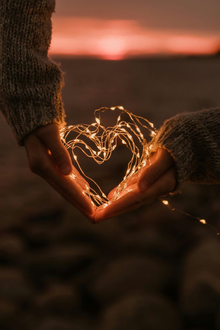 夕陽下用燈串捧成心形的雙手，呼應文章探討感情付出與戀愛腦